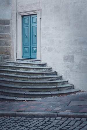 A vertical shot of a concrete building with a patterned, blue door and stair