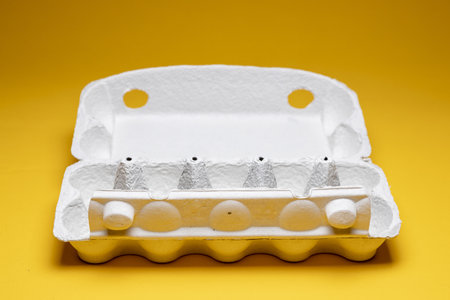 Open egg carton box in studio spot light against a seamless yellow backgroundの写真素材
