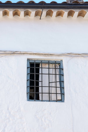A vertical shot of a window of a white building under the sunlight in Grazalema, Spainの写真素材