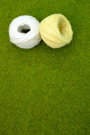 A vertical shot of yellow and white thread yarns on the grass with a copy space