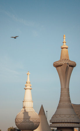A vertical shot of The Dallah Coffee Pot in Abu Dhabi under the clear sky with a flying birdの写真素材