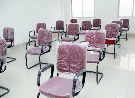 A closeup shot of a conference room with new red chairs set in concept of social distance