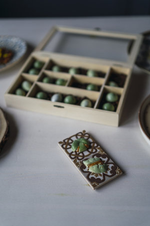A vertical shot of cut cookies on a small board on the table with a box of sweets on it