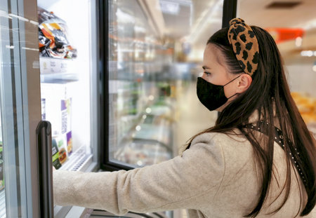 Young woman with black face mask in grocery store.の写真素材