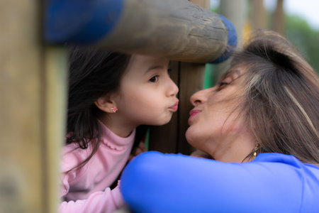 An adorable Latin mother and daughter playing in a parkの写真素材
