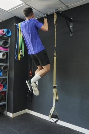 A fit young man in sportswear doing a workout in a gym