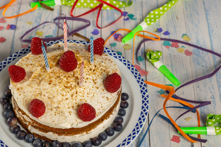 birthday cake with cream and raspberry sponge cake with candles and streamers