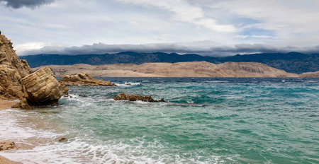 A beautiful view of the sea surrounded by rocky cliffs under a cloudy skyの写真素材