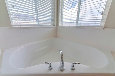 A minimalistic bathroom interior design in white color with a bathtub overlooking windowsの写真素材