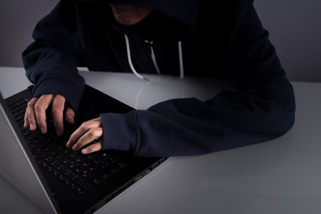 A closeup of a hacker typing and working on his laptopの写真素材