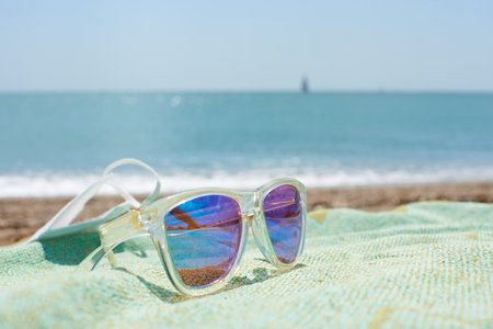 A closeup shot of funky sunglasses on the beach towel on a sand beachの写真素材
