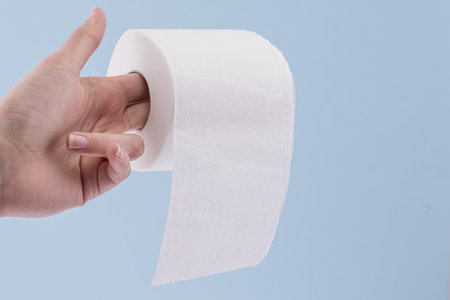 A closeup shot of a women's hand golding a roll of toilet paperの写真素材