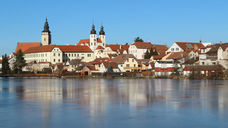 A view to the castle above the frozen pond in Telc, Czech republicの写真素材