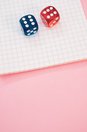 A closeup shot of two rolling dices on a notebook isolated on a pink backgroundの写真素材