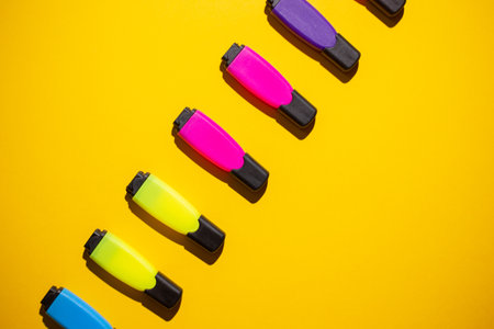 A top view of multicolored markers on a yellow work tableの写真素材