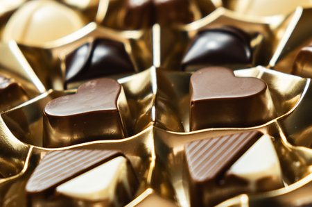 A high angle shot of heart-shaped chocolate bonbons in the golden plastic boxの写真素材