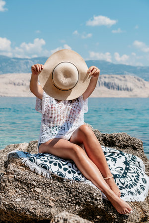A vertical shot of a beautiful sexy woman with a hat and sunglasses enjoying summer seaの写真素材