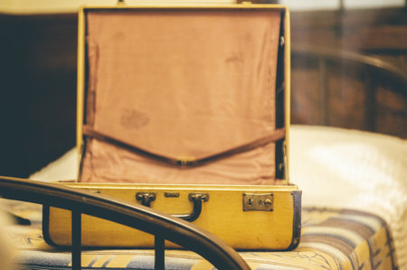 An old vintage yellow suitcase on a bedの写真素材