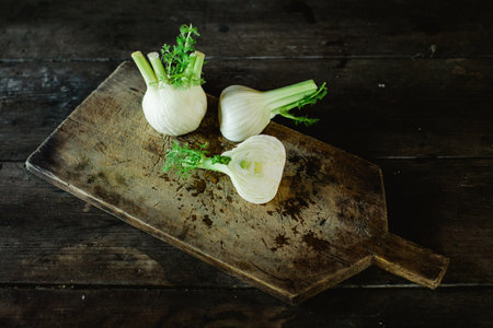 A high angle shot of fresh garlic on a wooden board and tableの写真素材