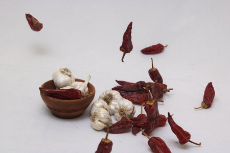 A pile of dried chili peppers and garlic on a white surface