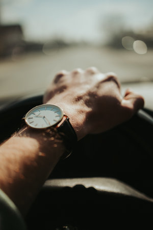 A selective focus of a male hand with a wristwatch holding the steering wheel of a carの写真素材