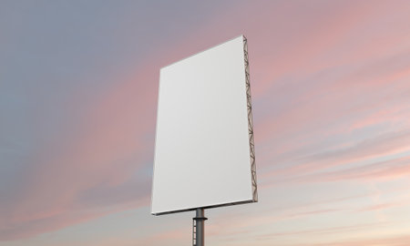 A low angle shot of a blank billboard with space for text under a cloudy sky during a beautiful pink sunsetの写真素材