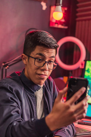 A vertical shot of a young gamer male going live from his phoneの写真素材