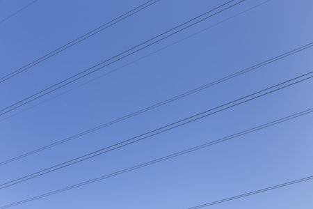electric cables, the cables draw perpendicular parallel lines in the blue sky
