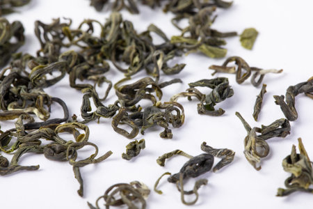 A closeup of dried biluochun green tea leaves on a white surfaceの写真素材
