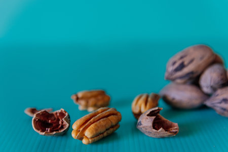 A closeup shot of whole and shelled pecans on a green surfaceの写真素材