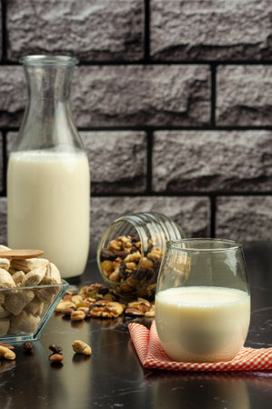 A vertical shot of a quick breakfast consisting of milk, nuts and cookies on a marble counterの写真素材