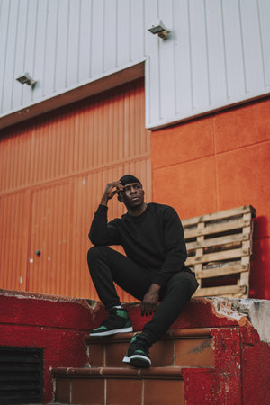 A vertical shot of an athletic Black man sitting on concrete stepsの写真素材
