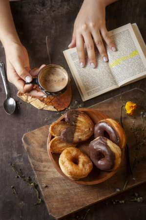 A vertical shot of a woman enjoying a relaxing rustic breakfast while reading a bookの写真素材