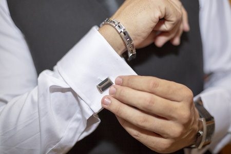 A closeup shot of a man buttoning his shirt cuffs
