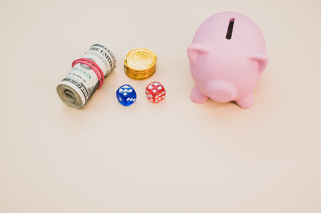 A piggy bank with dice, gold coins, and rolled up dollars next to itの写真素材