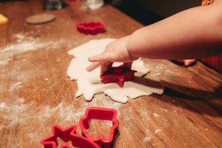A closeup shot of a child using cookie cutters on the doughの写真素材