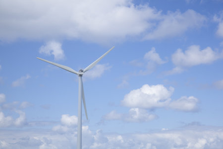 A wind turbine with a cloudy sky during the daytime