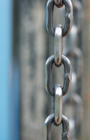 A vertical shot of a metal chain with reflection in the backgroundの写真素材