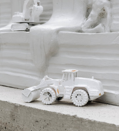 White painted toys representing construction machinery at a construction site.