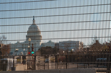 Slightly abstract view through a fence showing the surrounded Capitol Buildingの写真素材