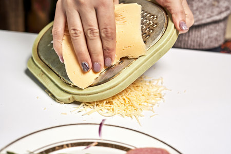 A chef shredding cheese to sprinkle on pizzaの写真素材
