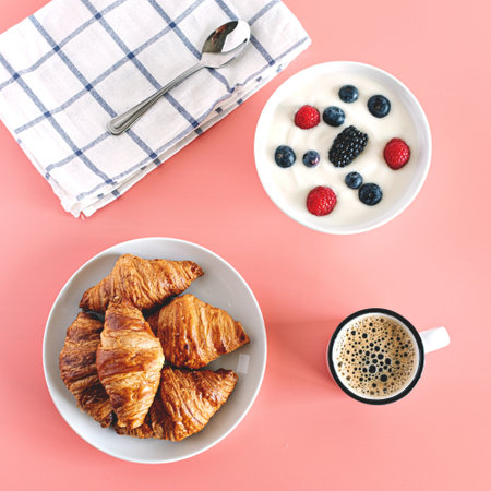 A top view of delicious croissants, hot coffee and yogurt with berries for breakfastの写真素材