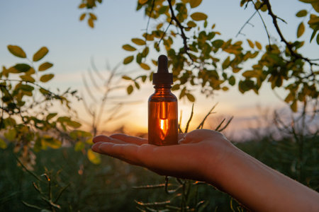 A woman's hand holding a dropper bottle with cosmetic avocado oilの写真素材