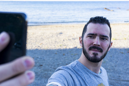 A closeup shot of a Caucasian male taking a selfie on the beachの写真素材
