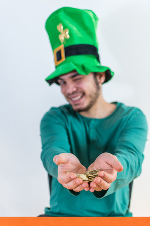 A lovely man in a leprechaun hat wearing a green costume for a party offering gold coins on St.Patrick's dayの写真素材