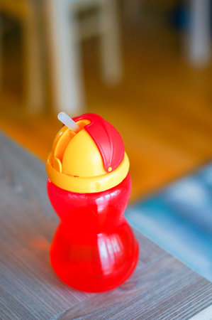 Red plastic child straw drinking cup on wooden tableの写真素材