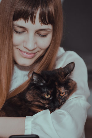 A vertical shot of a smiling young Caucasian female holding a black catの写真素材