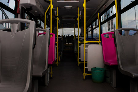 An inside view of an empty passenger bus with gray seatsの写真素材
