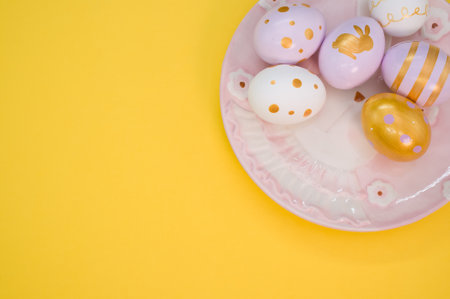 Decorated eggs on white plate isolated on yellow backgroundの写真素材