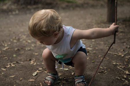 A closeup shot of a Caucasian boy holding a stick in the outdoorsの写真素材